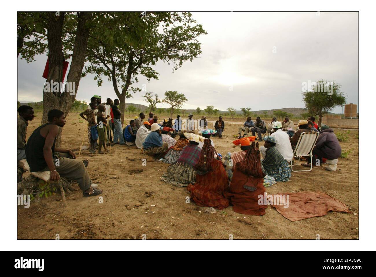 Appel de Noël indépendant...... Développement rural intégré et conservation de la nature (IRDNC) en Namibie.Colin Nott Coordonnateur du programme de l'aire de répartition holistique de l'IRDNC et Anna Davis à la réunion de la communauté d'Eora sous les arbres de Mapani dans le district d'Otjimanda de la bande de Caprivi. Photo de David Sandison novembre 2004 Banque D'Images