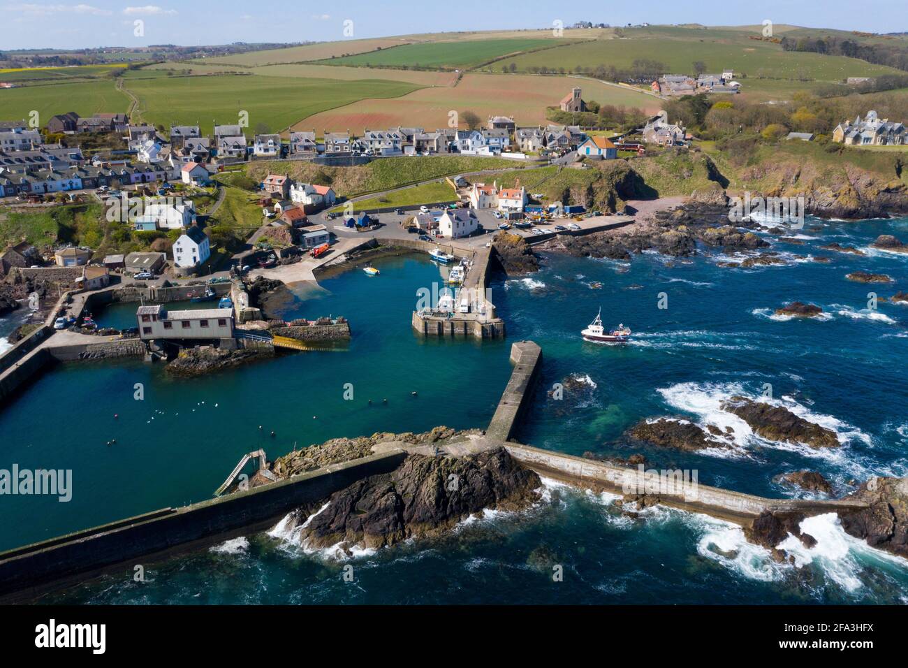 Vue aérienne montre un bateau de pêche qui retourne au port de St Abbs sur la côte du Berwickshire, Écosse, Royaume-Uni. Banque D'Images Vue aérienne montre un bateau de pêche qui retourne au port de St Abbs sur la côte du Berwickshire, Écosse, Royaume-Uni. Banque D'Images