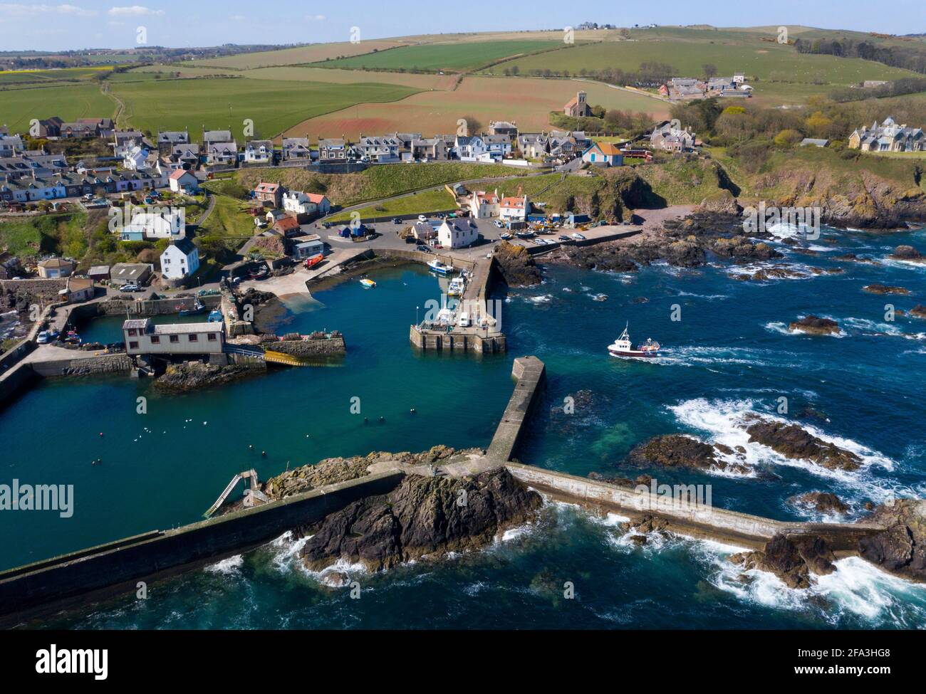 Vue aérienne montre un bateau de pêche qui retourne au port de St Abbs sur la côte du Berwickshire, Écosse, Royaume-Uni. Banque D'Images Vue aérienne montre un bateau de pêche qui retourne au port de St Abbs sur la côte du Berwickshire, Écosse, Royaume-Uni. Banque D'Images
