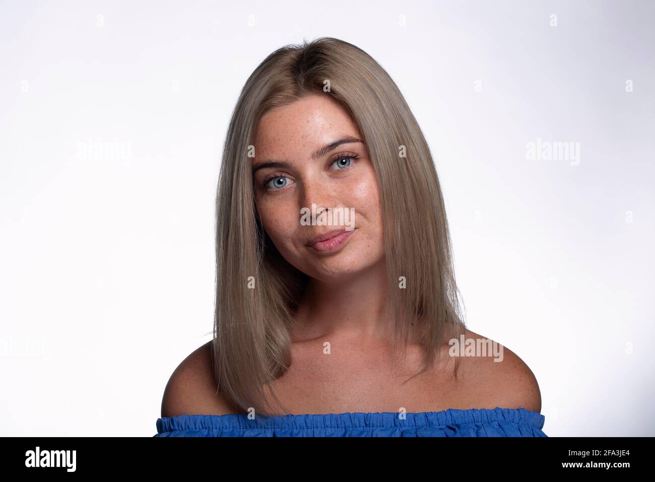 Belle fille avec des taches de rousseur montre des émotions devant le appareil photo sur fond blanc Banque D'Images