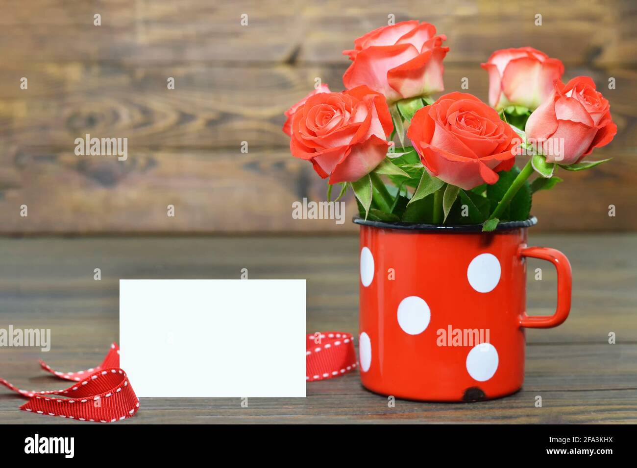 Carte de fête des mères avec roses rouges dans une tasse vintage Banque D'Images