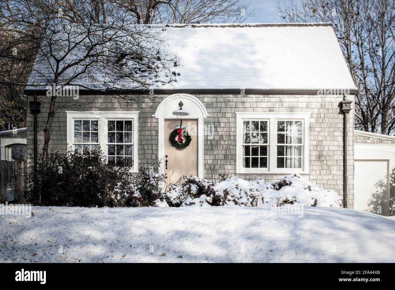 Petit cottage vintage dans la neige avec bardeaux en bois et couronne de Noël. Banque D'Images