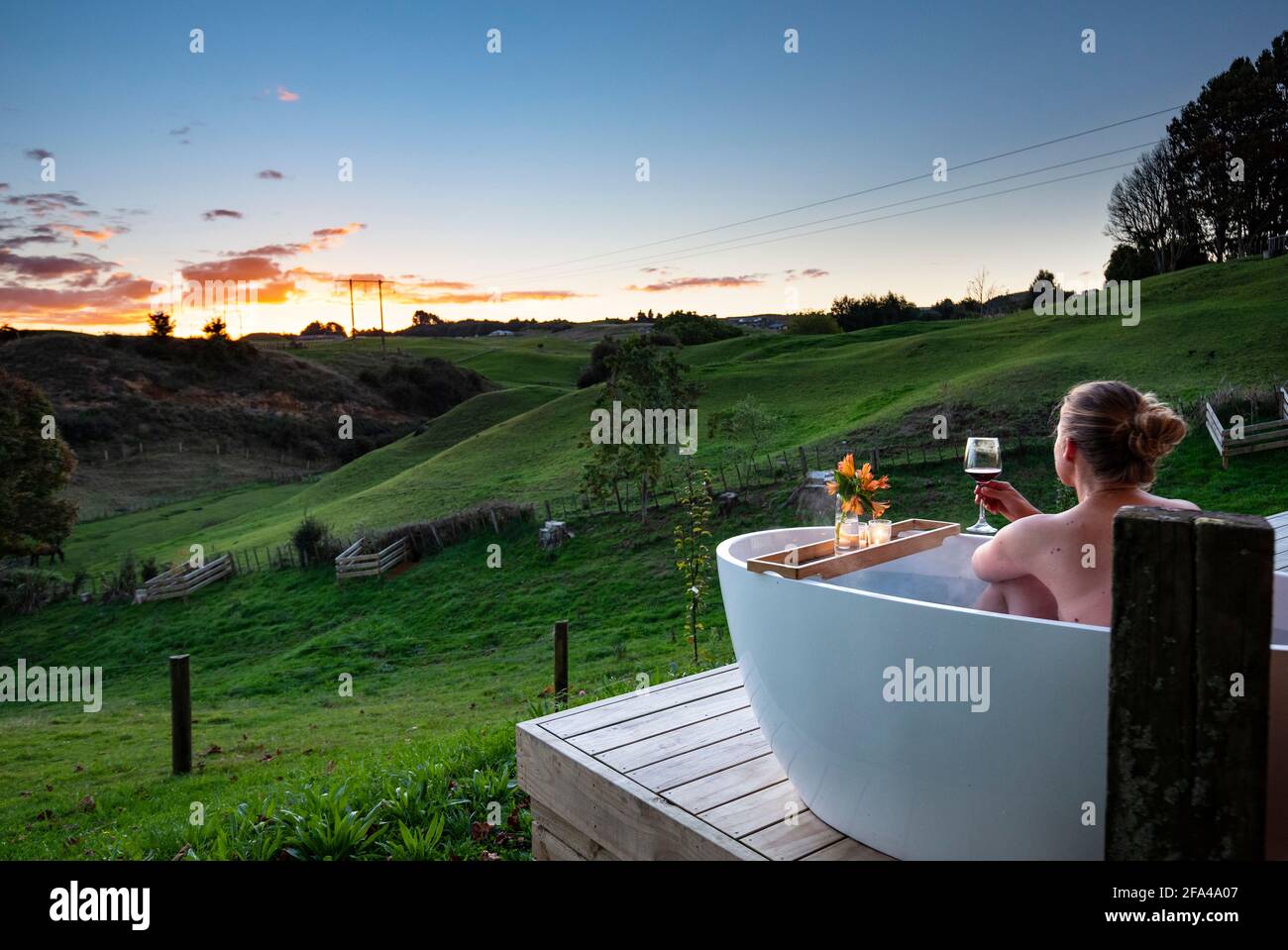 Femme dans le bain extérieur regardant le coucher du soleil, Rotorua, Nouvelle-Zélande Banque D'Images