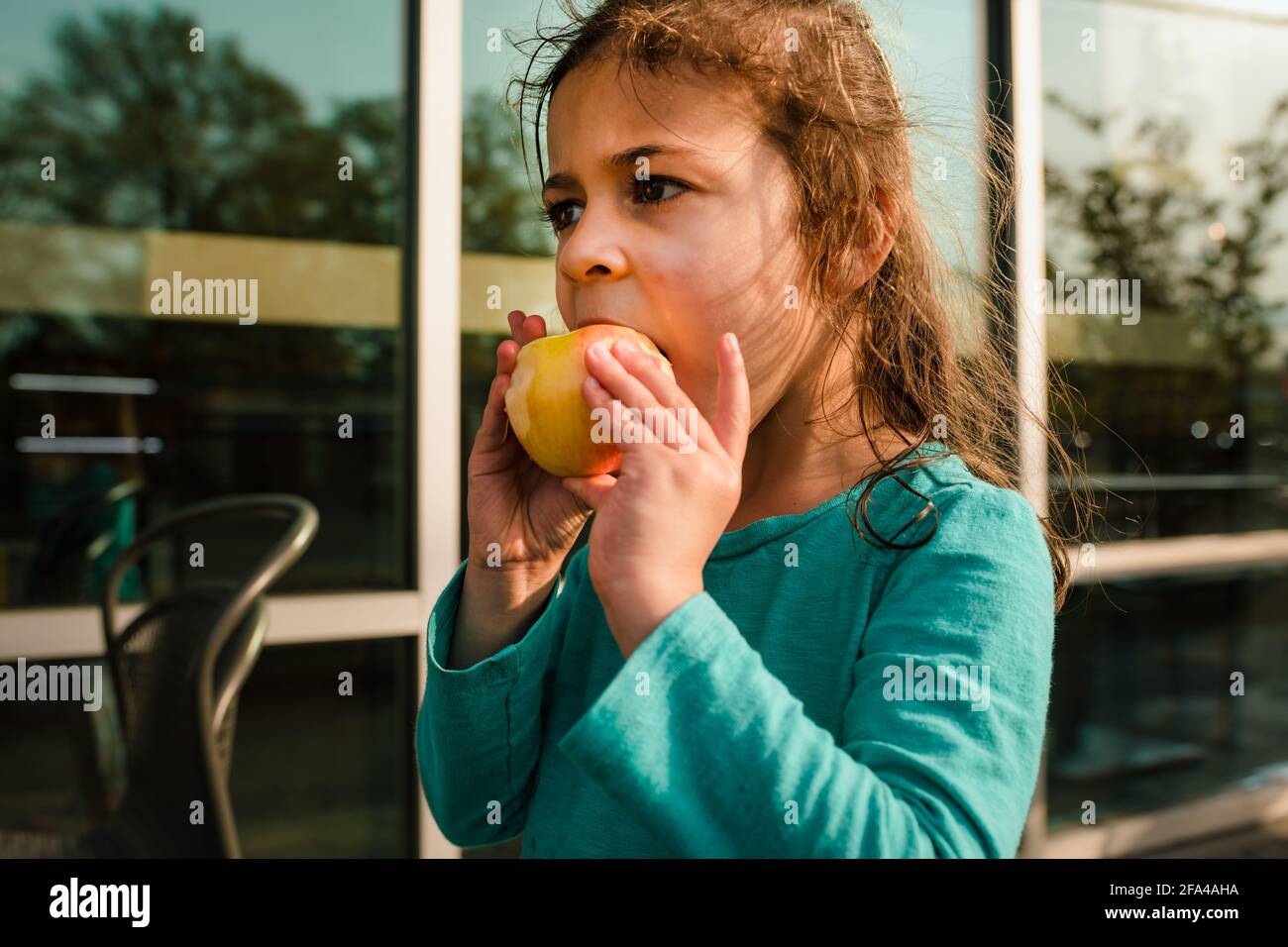 Petite fille mangeant de la pomme sur la terrasse extérieure Banque D'Images