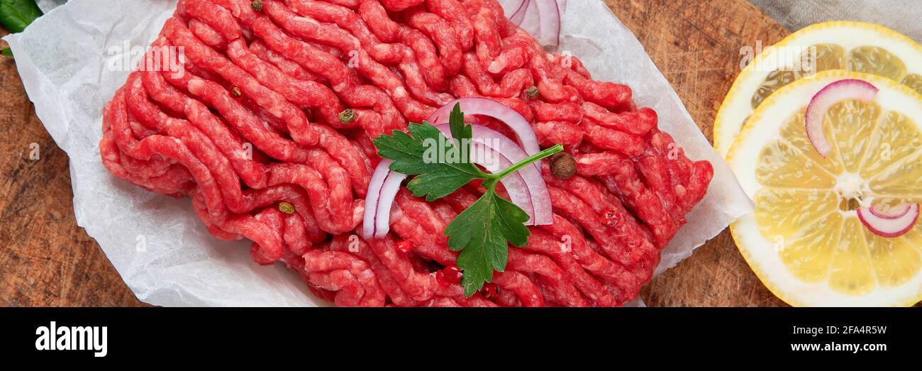 Viande hachée crue avec épices, légumes et herbes sur fond sombre. Ingrédients pour la cuisine concept. Vue de dessus, panorama, bannière Banque D'Images