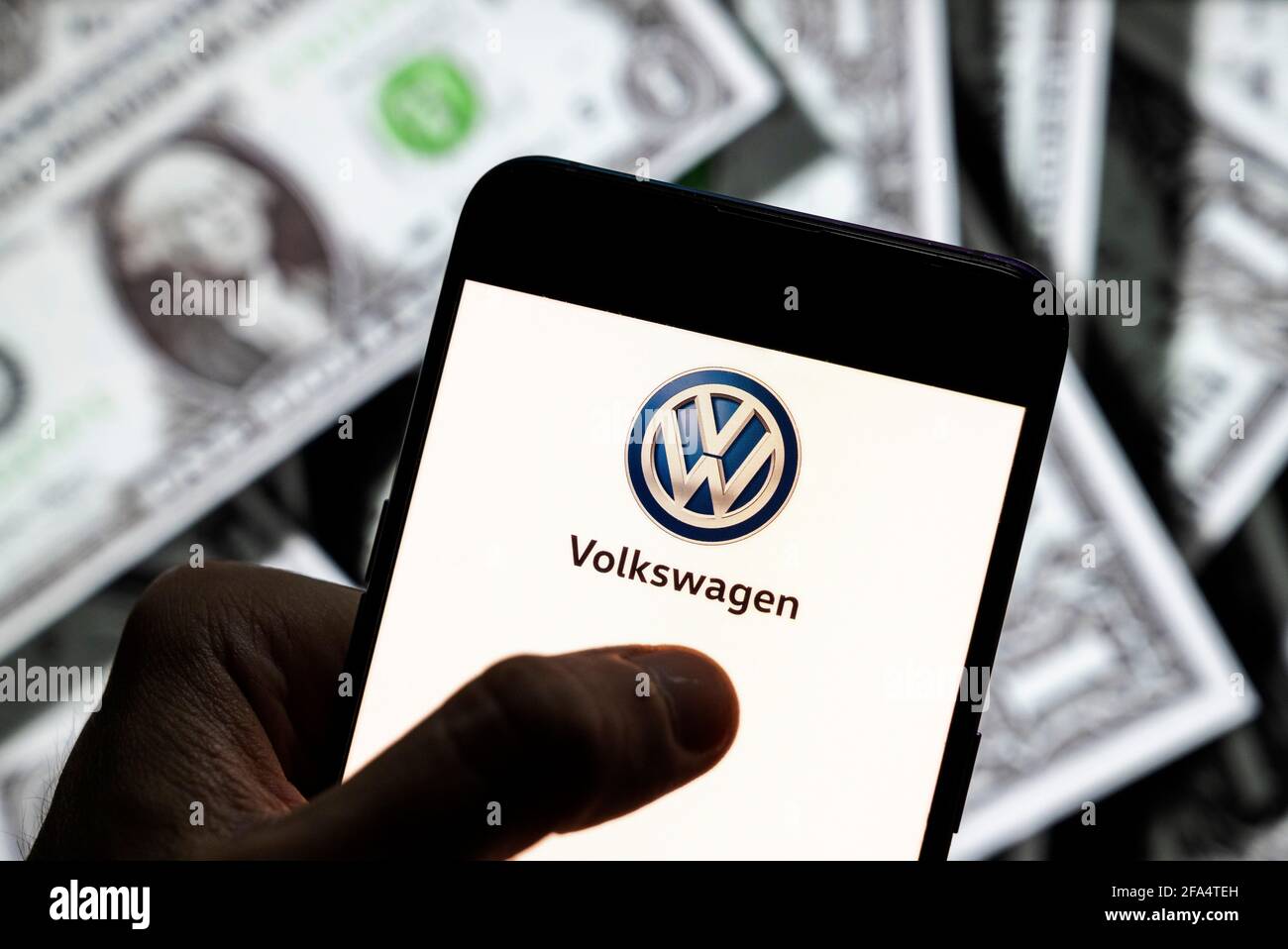 Dans cette illustration, le logo Volkswagen du constructeur automobile allemand vu sur un écran d'appareil mobile Android avec la devise de l'icône dollar des États-Unis, symbole d'icône $ en arrière-plan. Banque D'Images