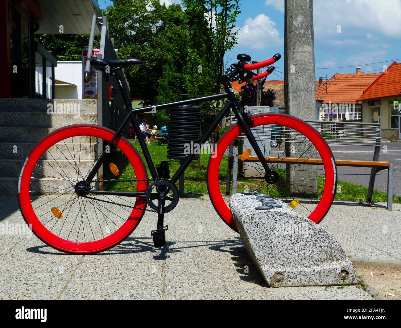 vélo moderne et élégant avec roues rouges skinny. concept sport, extérieur et entraînement. fond urbain. porte-vélo en béton préfabriqué. arbre vert derrière Banque D'Images