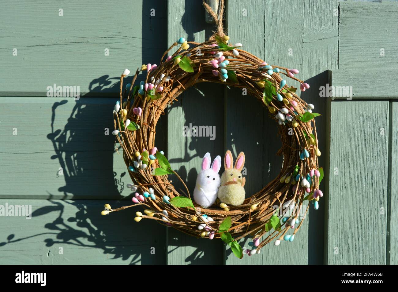 Couronne de Pâques avec deux lapins, accrochée sur une vieille porte verte Banque D'Images