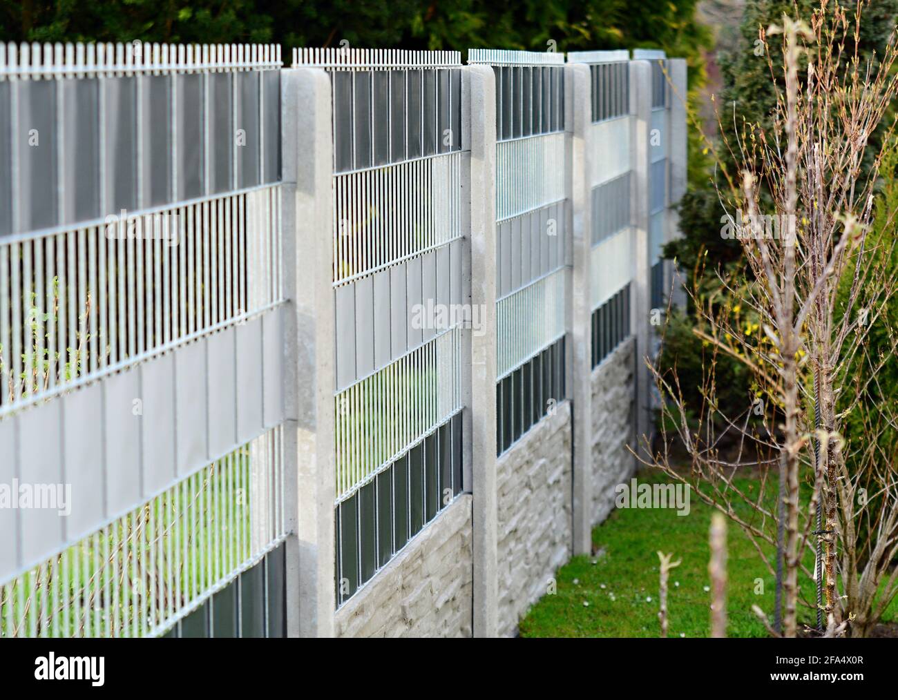 Clôture de jardin faite avec des panneaux de clôture en fil galvanisé décoratif insérés dans les colonnes de béton. Banque D'Images