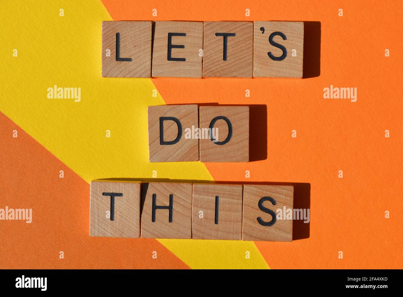 Faisons ceci, des mots de motivation en lettres de l'alphabet en bois isolées sur fond jaune et orange Banque D'Images