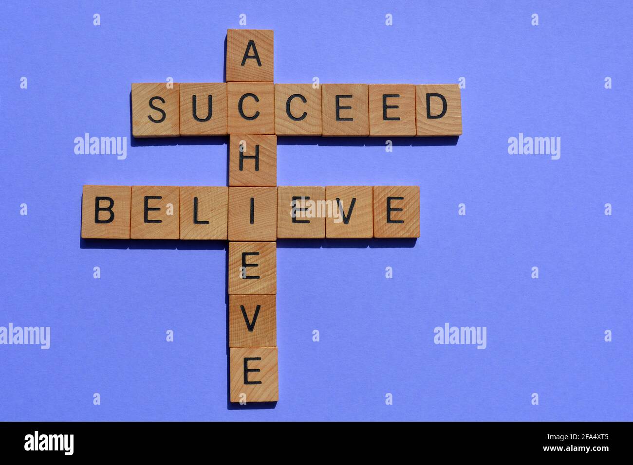 Croyez, réalisez, réussissez, motivational mots en bois alphabet lettres en forme de mots croisés isolé sur fond simple Banque D'Images