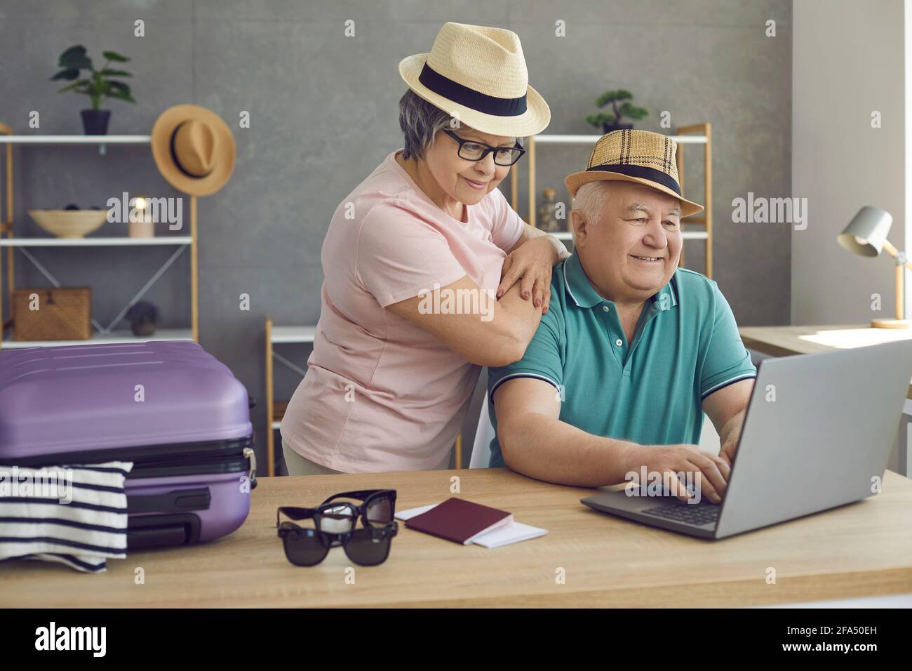 Les vieux couples utilisent un ordinateur portable pour acheter une excursion, un billet d'avion et réserver un hôtel à la maison Banque D'Images