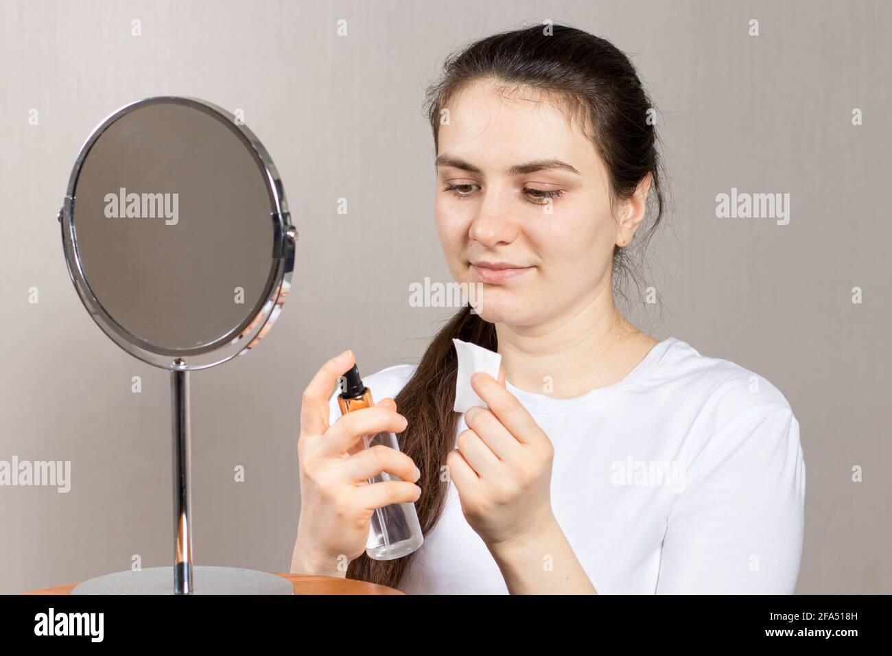 Une femme de 25 ans tient un tonique du visage et du cou et un tampon de coton. Anti-rides soins de la peau, vitamines et acides pour le visage Banque D'Images