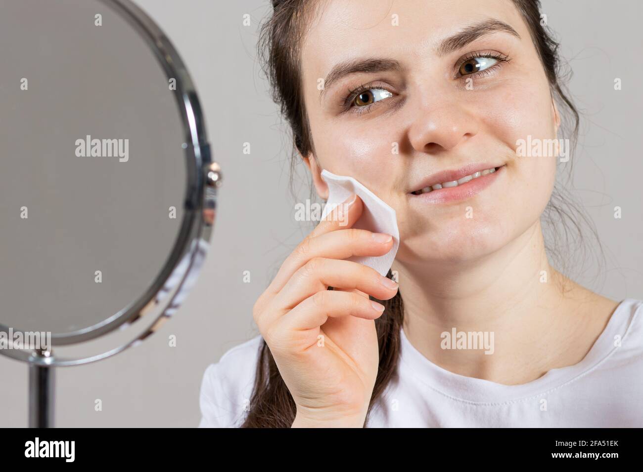 Une femme de 25 ans tient un tonique du visage et du cou et un tampon de coton. Anti-rides soins de la peau, vitamines et acides pour le visage Banque D'Images