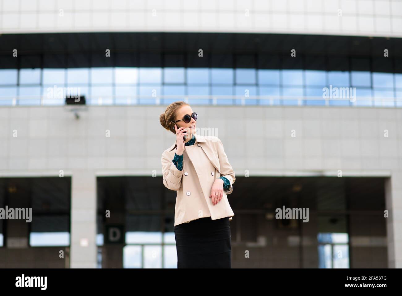 Jeune femme d'affaires belle avec des lunettes de soleil, téléphone, ordinateur portable, tasse de café dans la rue de la ville Banque D'Images
