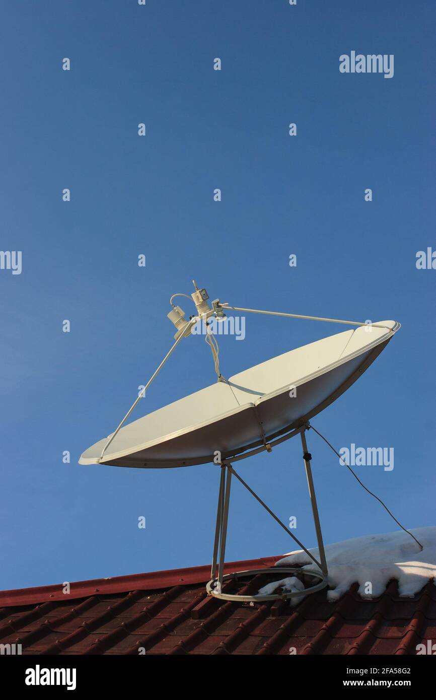 Plat satellite sur le toit d'une maison en hiver. Banque D'Images