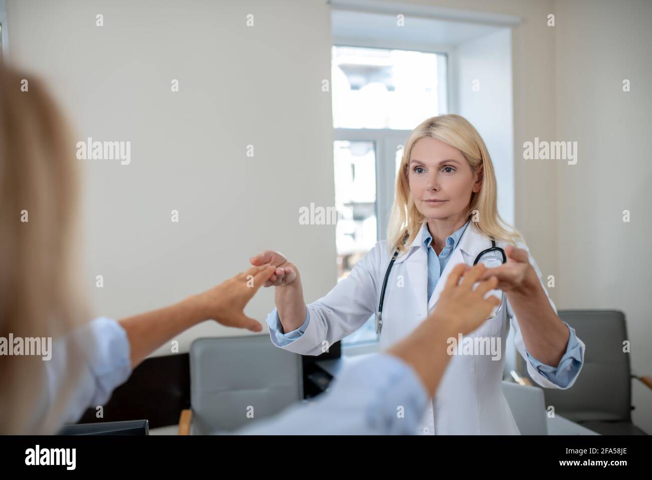 Le médecin touche les doigts du patient au-dessus des bras étirés Banque D'Images
