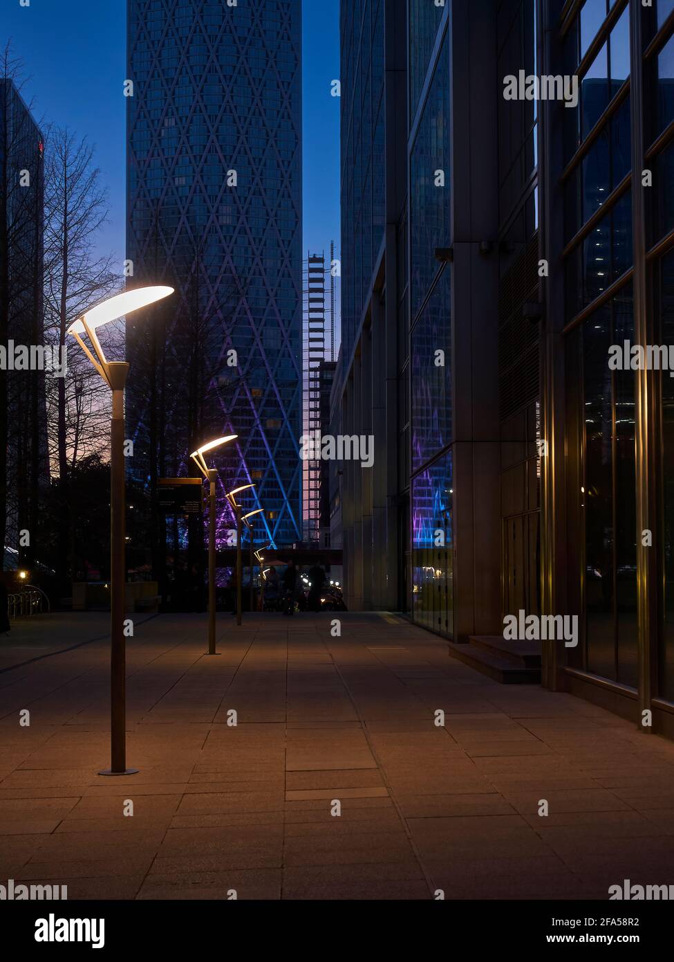 Une vue le long d'une rue vide, déserte au crépuscule, entourée par les tours cyclopéennes de Canary Wharf. Banque D'Images