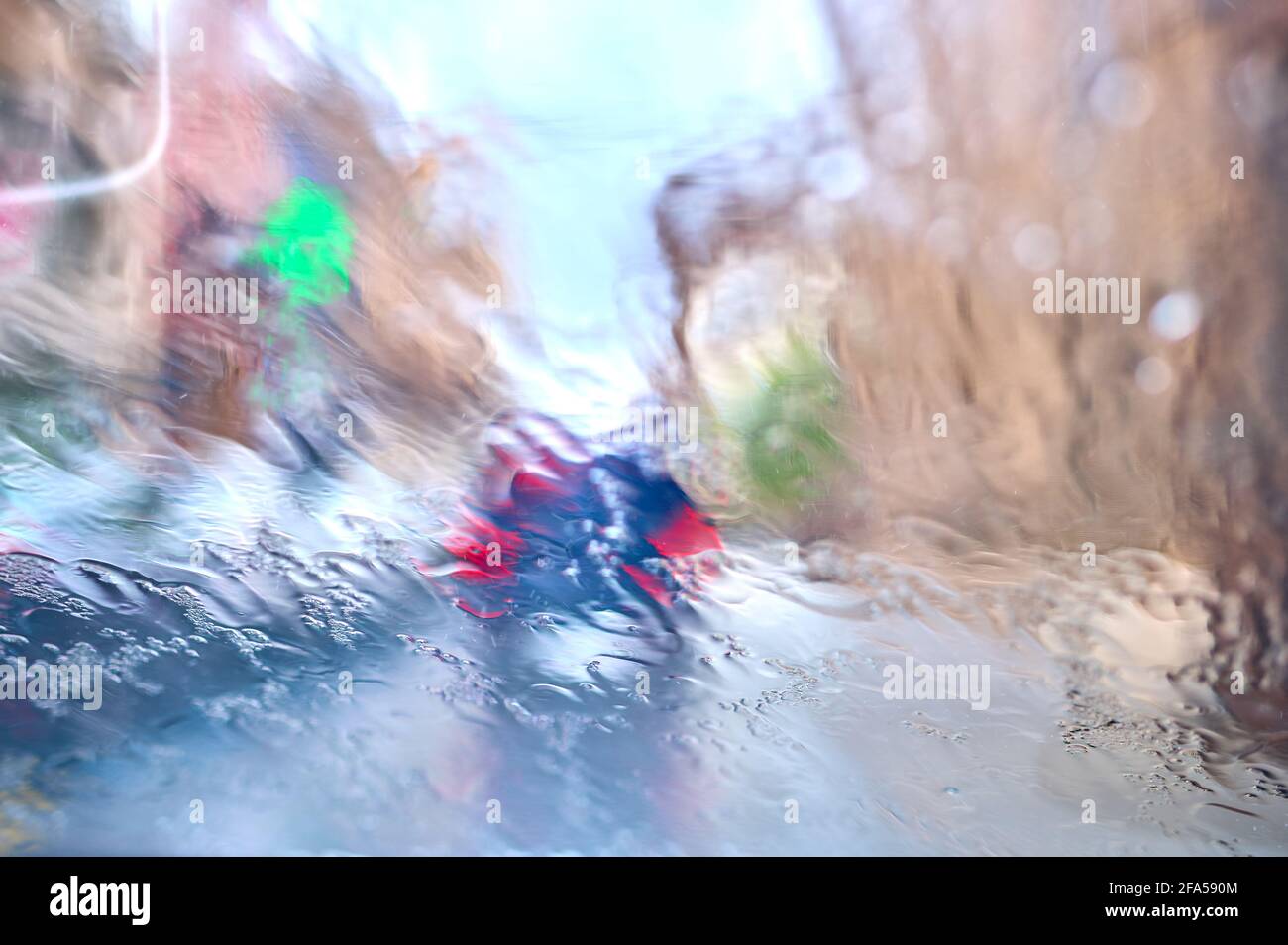 détail des gouttes de pluie sur le verre d'une voiture avec véhicules devant avec feux allumés Banque D'Images