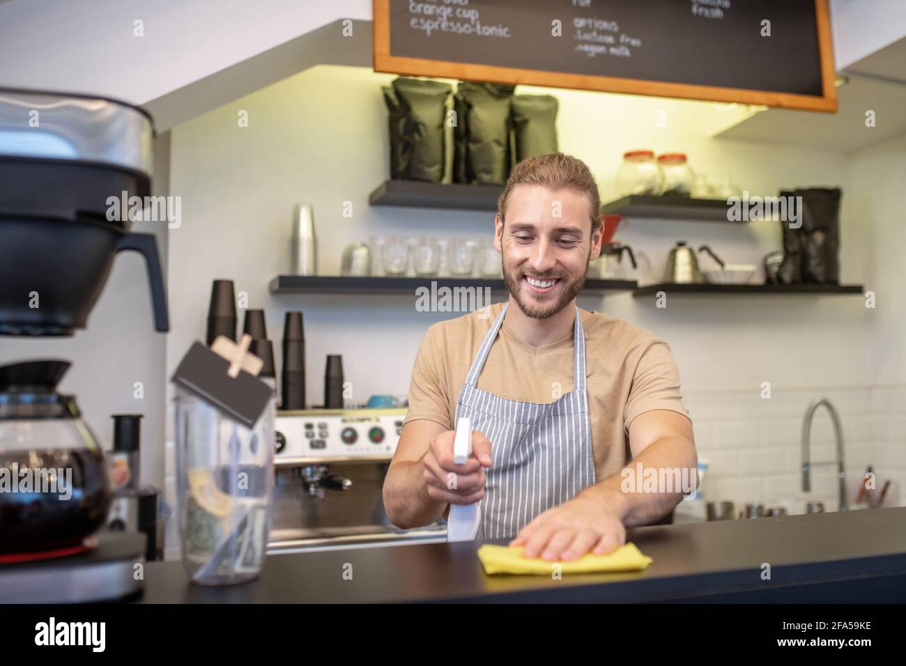 Homme joyeux qui fait du nettoyage humide au bar Banque D'Images