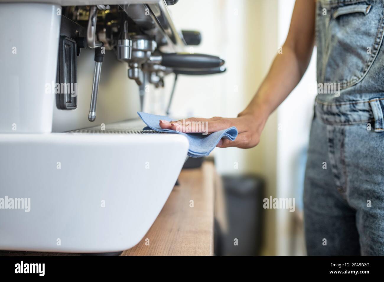 Femme main avec serviette coulissante sur la cafetière Banque D'Images