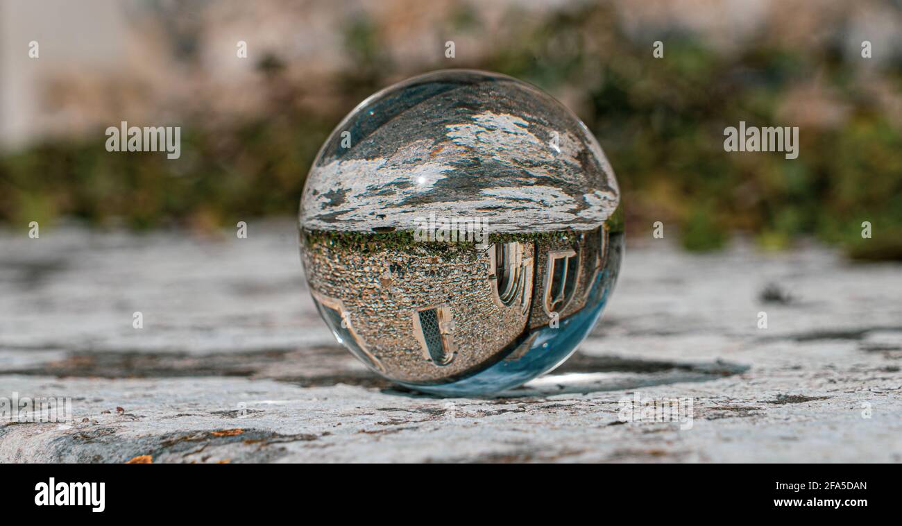 Boule de photo en cristal sur la surface en granit gris reflétant l'image de Église et bâtiment historique sous le soleil d'été Banque D'Images