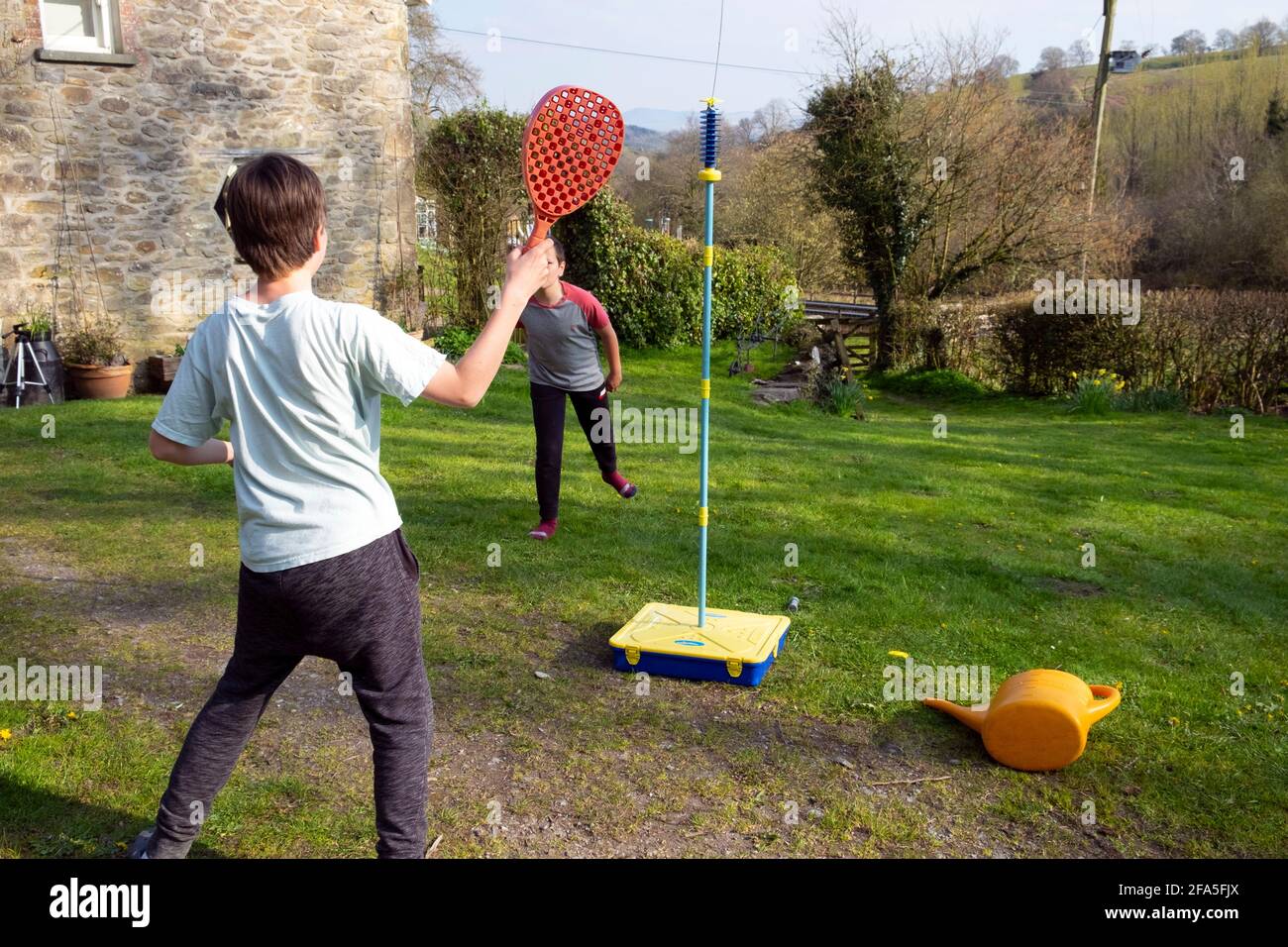 Deux garçons de 11 ans jouant au swingball avec des chauves-souris dans un Jardin rural au printemps après les restrictions de verrouillage facilité 2021 Carmarthenshire PAYS DE GALLES ROYAUME-UNI KATHY DEWITT Banque D'Images