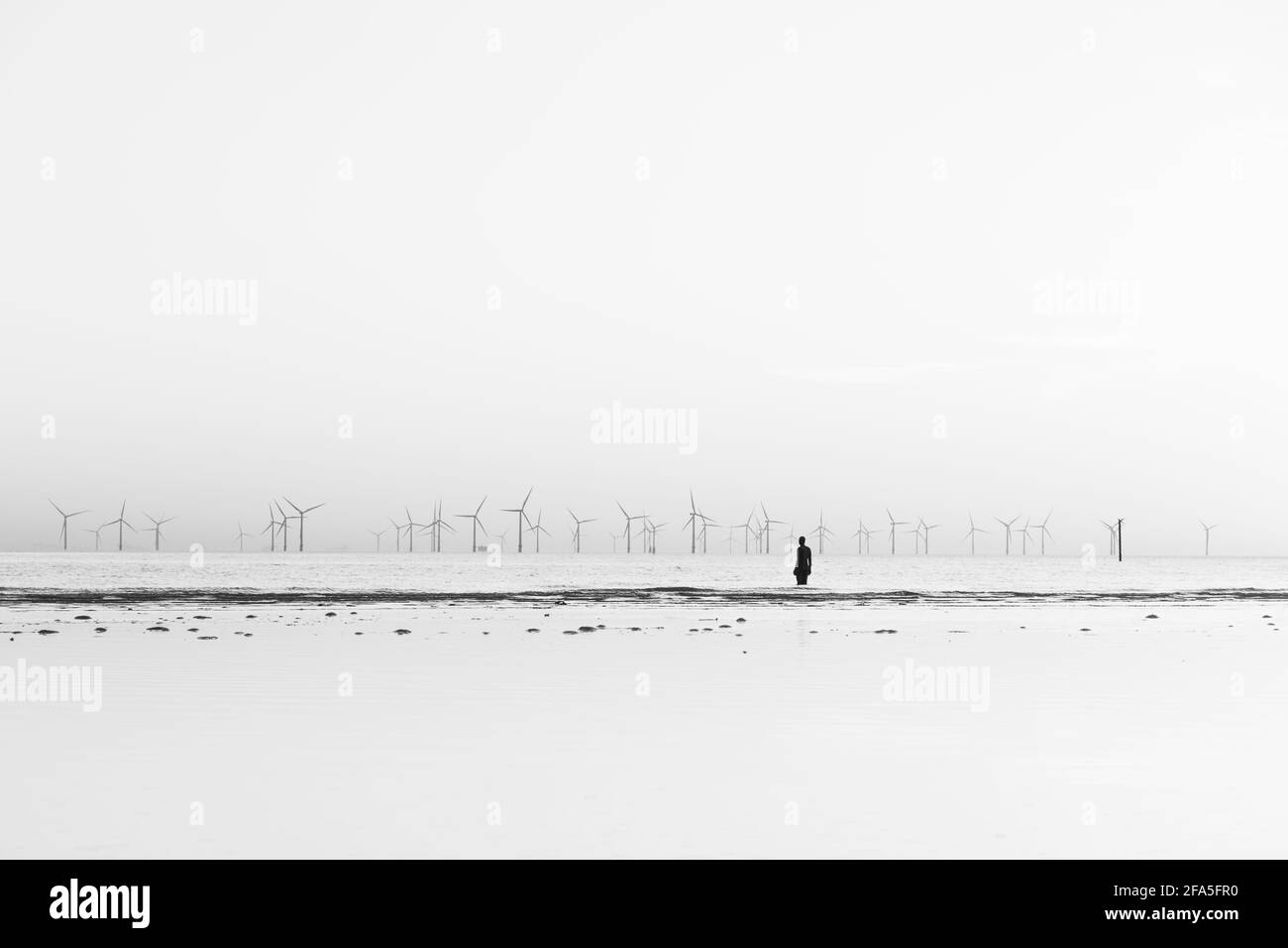 Un homme de fer vu sur la plage de Crosby à marée haute en avril 2021 face au parc éolien de Burbobank. Il fait partie d'un autre endroit, l'installation artistique Banque D'Images