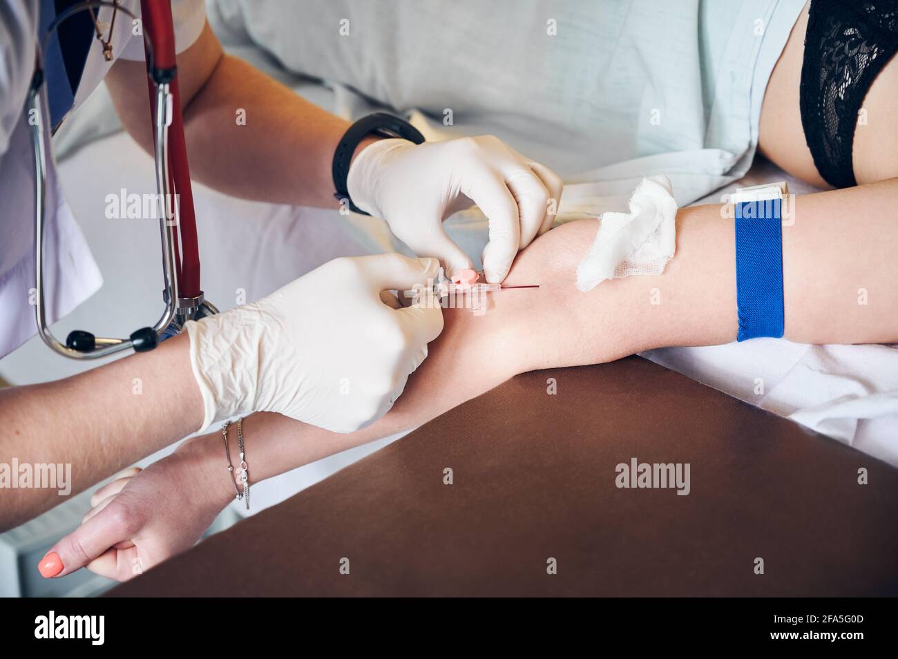 Gros plan des mains de l'anesthésiste dans des gants stériles injectant une dose d'anesthésique. Médecin insérant l'aiguille dans le bras du patient tout en injectant le médicament anesthésique avant l'intervention chirurgicale. Concept de médecine. Banque D'Images