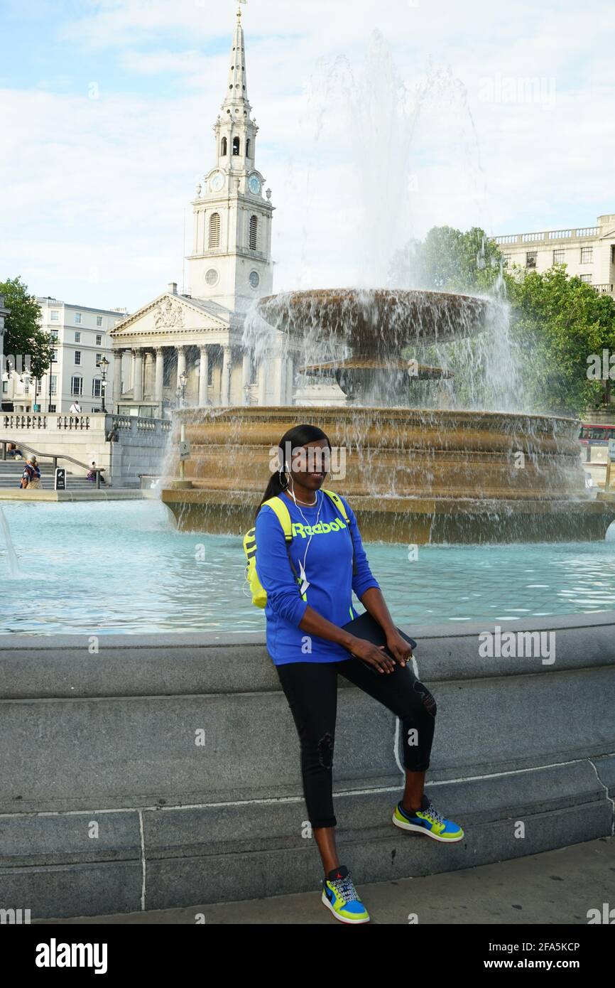 Une femme afro-caribéenne devant la fontaine de Trafalgar Square à Londres, Angleterre, U.K Banque D'Images