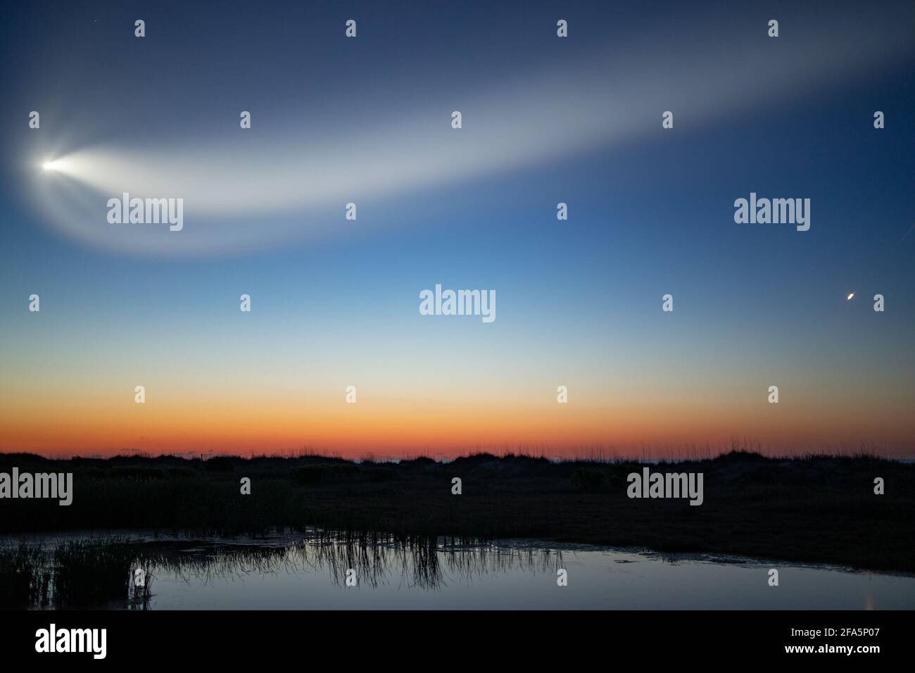 Sullivan's Island, Caroline du Sud, États-Unis. 23 avril 2021. La fusée Crew Dragon de SpaceX s'étend au large de la côte de l'île Sullivan pendant le coucher du soleil. La capsule a été lancée de la Floride à 5 h 49 et transporte quatre astronautes à la Station spatiale internationale. Crédit : SOPA Images Limited/Alamy Live News Banque D'Images