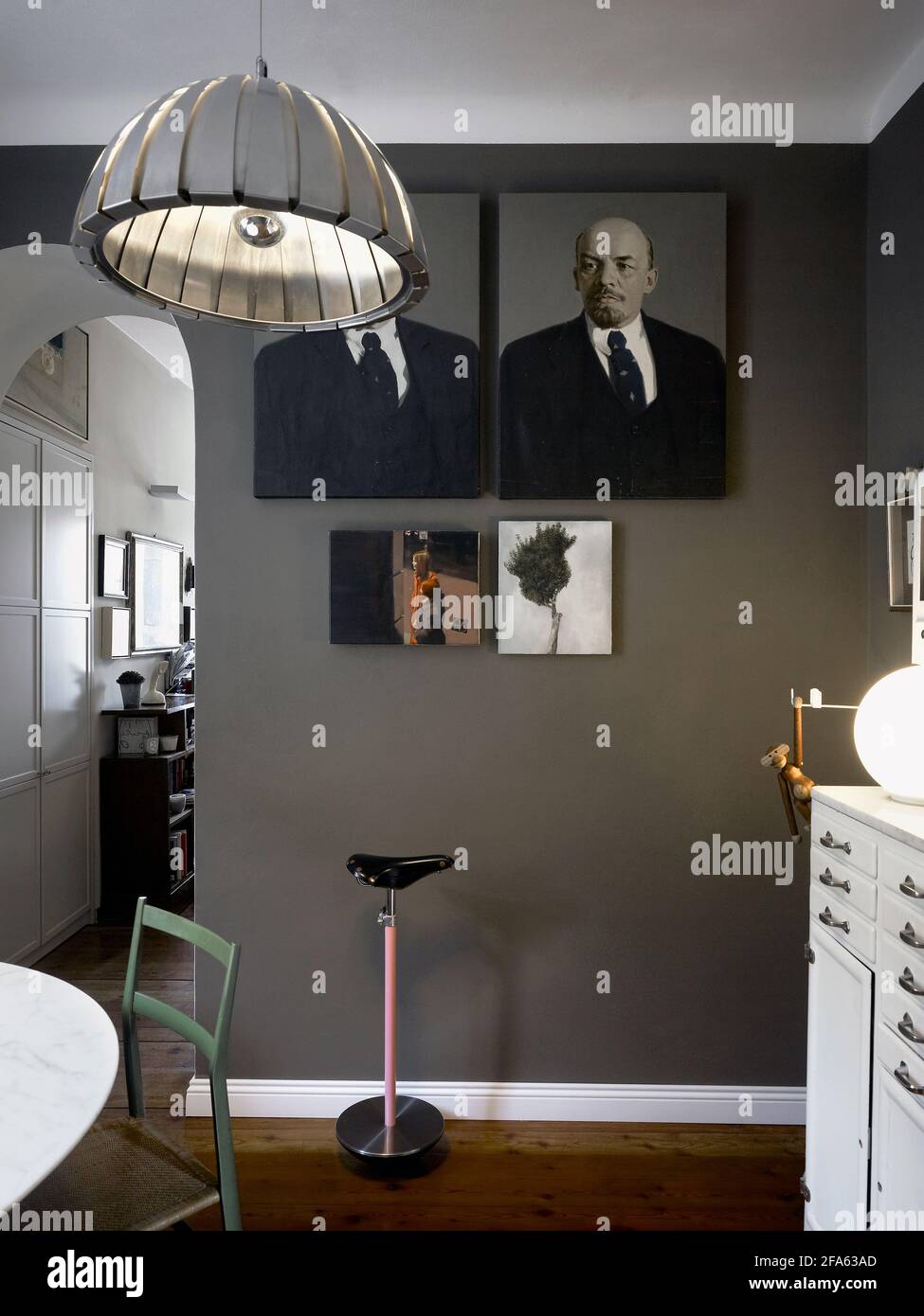 Intérieur d'une chambre dans un appartement à Milan Italie. Détail du mur avec une œuvre d'art avec le portrait de Lénine et le siège de selle de Zanotta Banque D'Images
