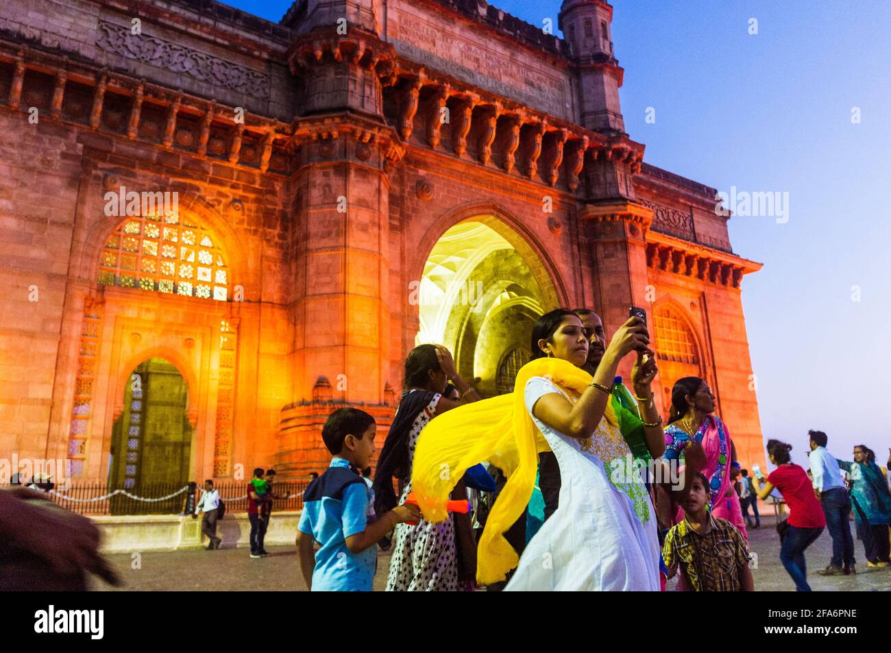 Mumbai, Maharashtra, Inde : les gens posent pour les selfies au crépuscule devant la porte illuminée de l'Inde arche monumentale construite entre 1913 et 1924 i Banque D'Images