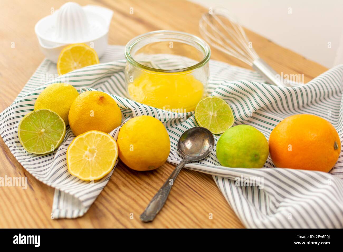 Beaucoup d'agrumes comme des citrons, des oranges et des limes sur une table en bois prête à être pressée pour le jus ou pour la cuisson, un verre de wtih citron caillé. Banque D'Images