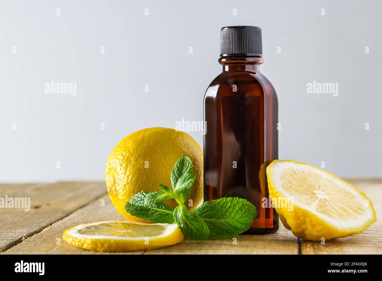 Huile aromatique avec citron et menthe sur fond de bois. Produit de relaxation et de spa. Banque D'Images