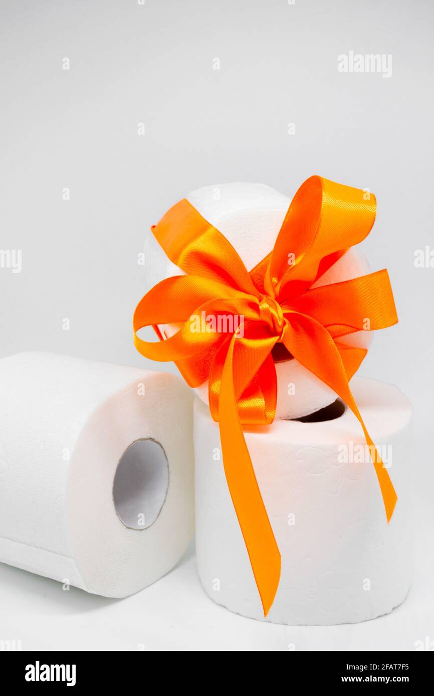 Plusieurs rouleaux de papier toilette perforé blanc. Un rouleau est attaché  avec un ruban de satin orange vif comme cadeau. Photo verticale Photo Stock  - Alamy