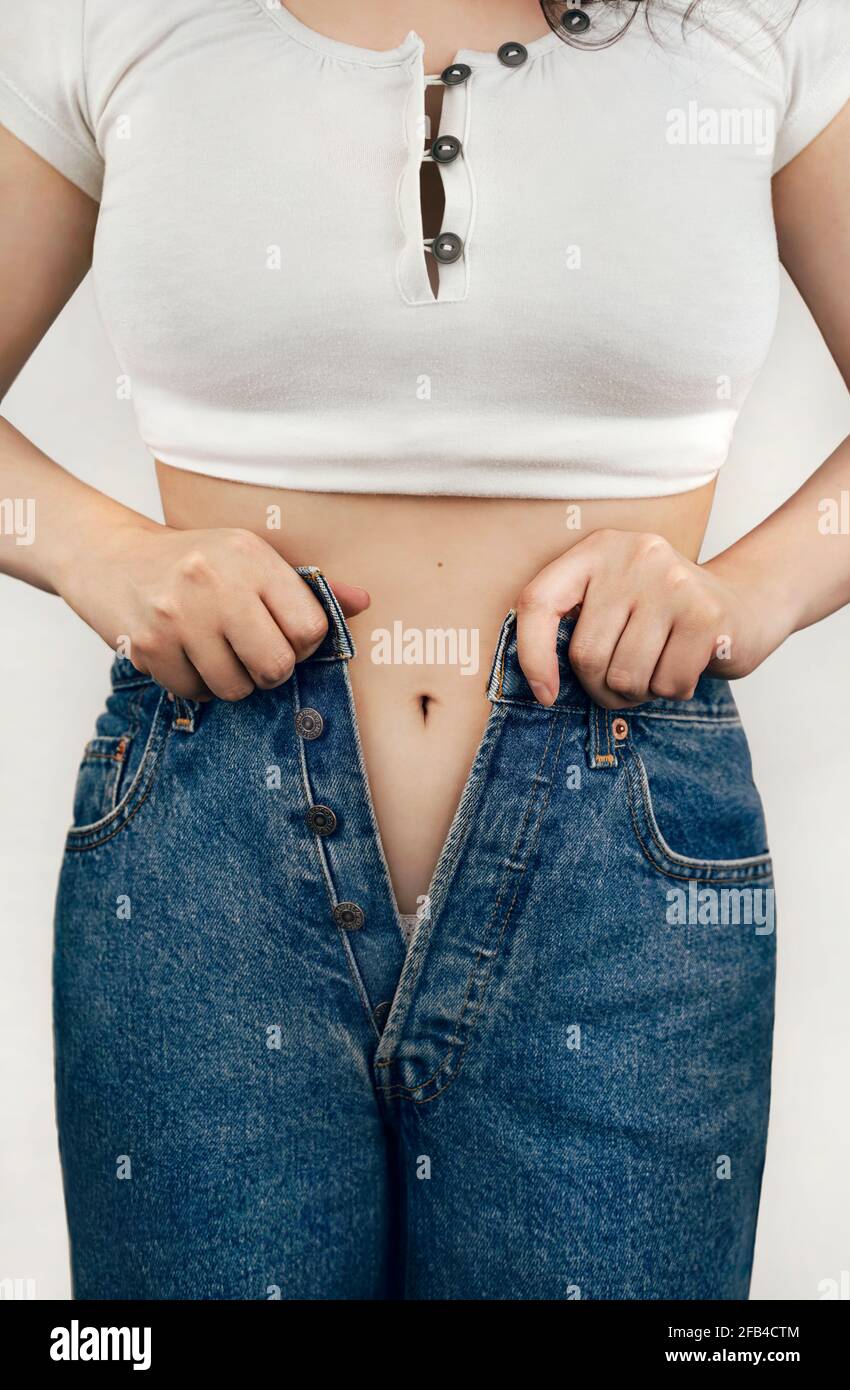 Jeune femme en blanc crop top essayant de boutons jeans Banque D'Images