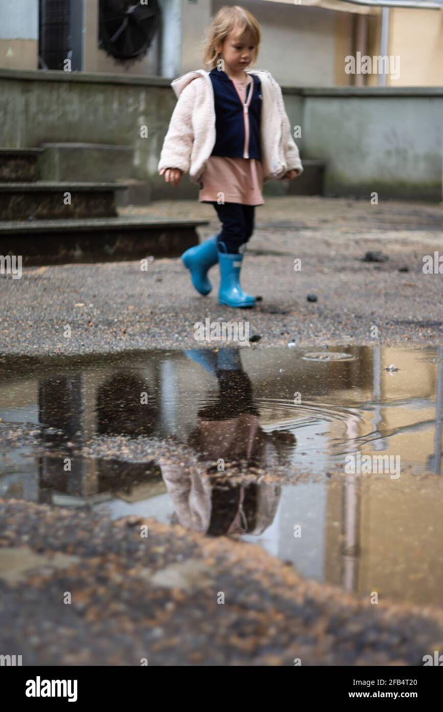 Réflexion d'une fille dans des bottes en caoutchouc marchant à côté de bas de porte Banque D'Images