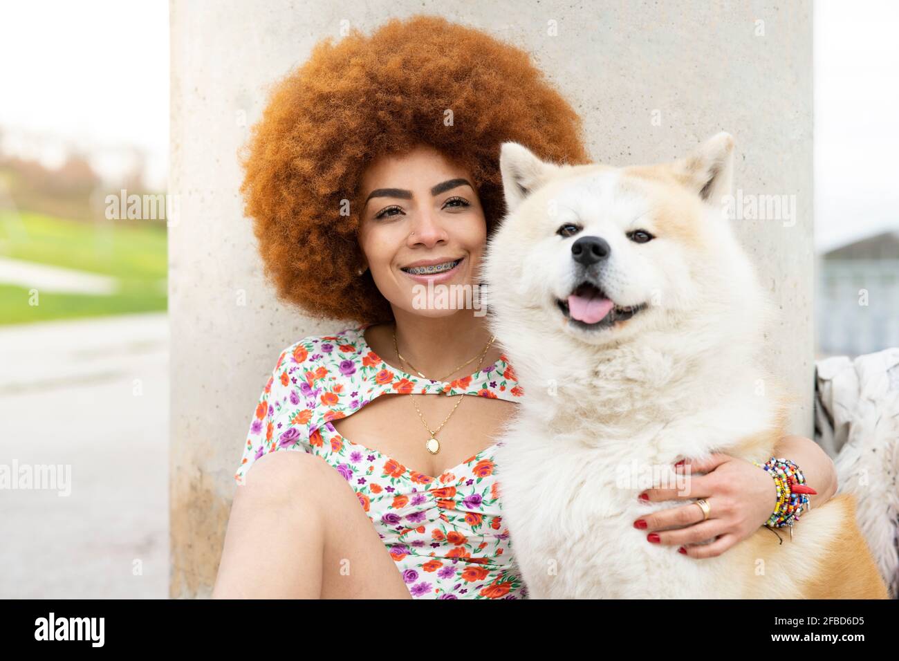 REDHEAD femme souriant assis avec un chien devant pilier Banque D'Images