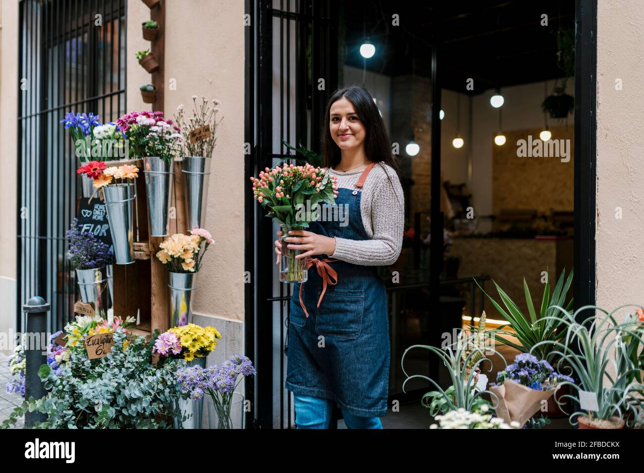 Jeune fleuriste femme tenant un vase en forme de fleur en se tenant au magasin Banque D'Images