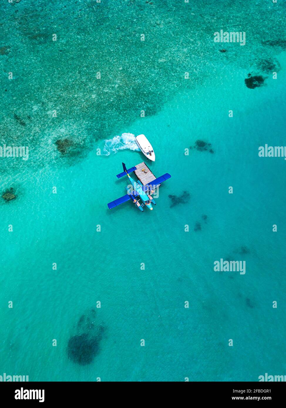 Vue aérienne du bateau à moteur approchant de l'hydravion flottant dans l'eau turquoise De l'atoll masculin Banque D'Images