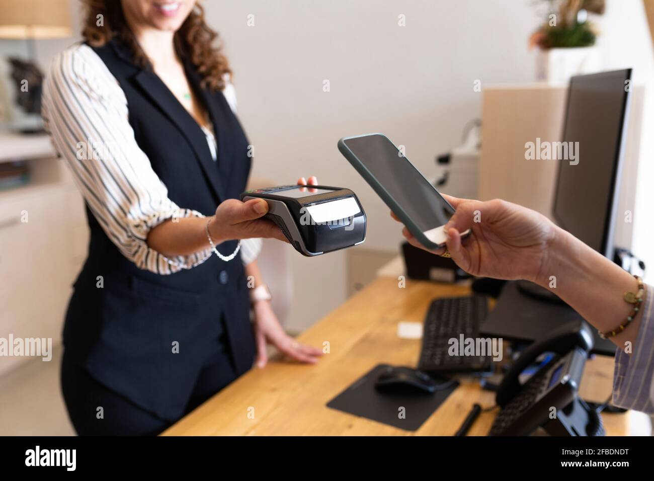 Femme d'affaires tenant le téléphone portable par lecteur de carte de crédit à l'hôtel réception Banque D'Images
