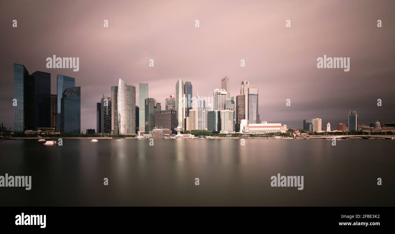 Singapour, longue exposition de Marina Bay au crépuscule avec des gratte-ciels en arrière-plan Banque D'Images