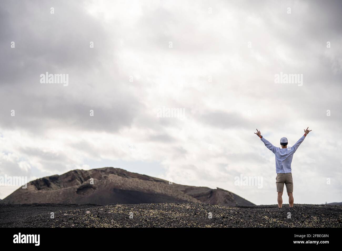 Touriste mâle aux bras étirés debout sur le paysage volcanique Banque D'Images