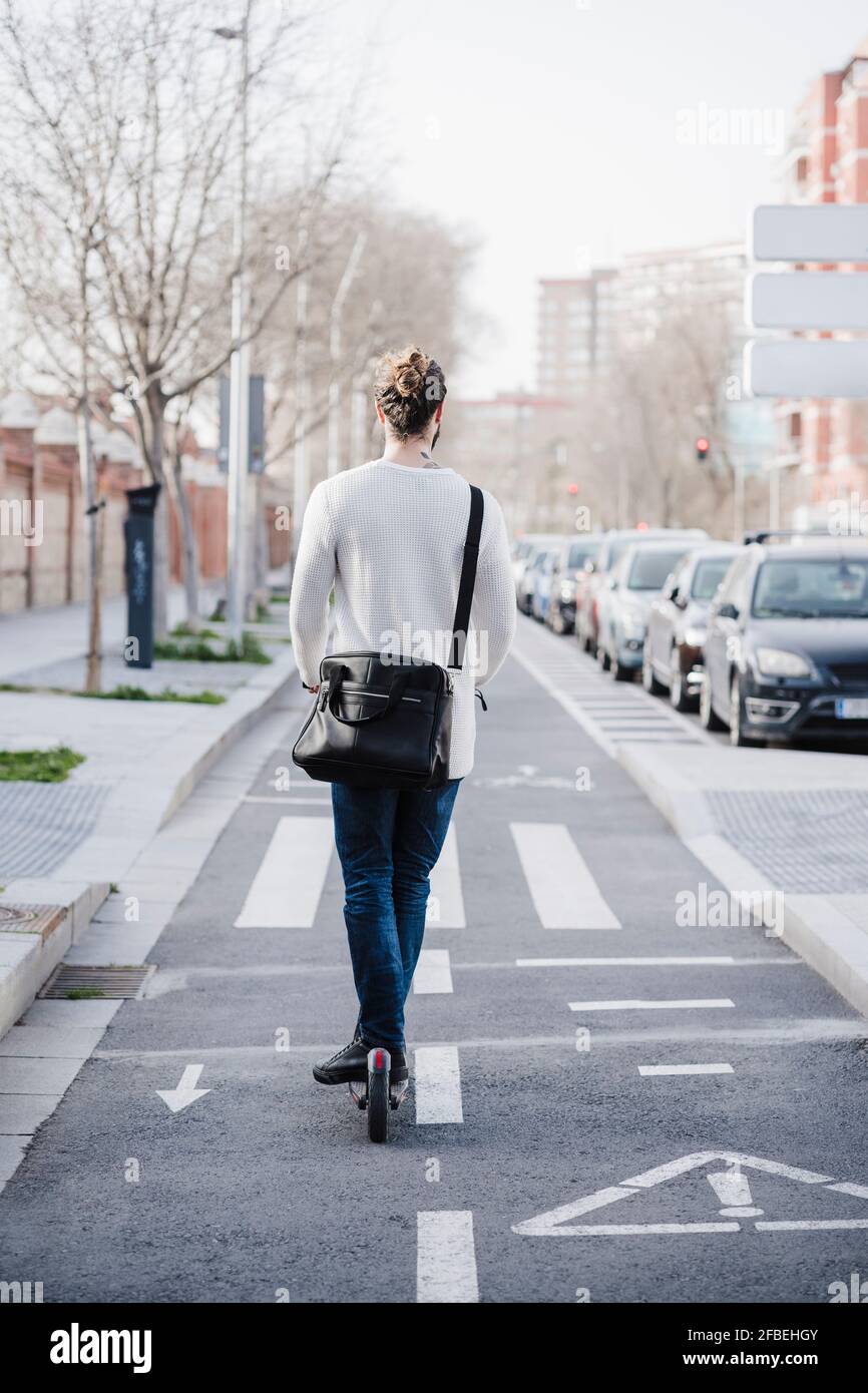 Homme moyen adulte qui roule sur route en scooter électrique Banque D'Images