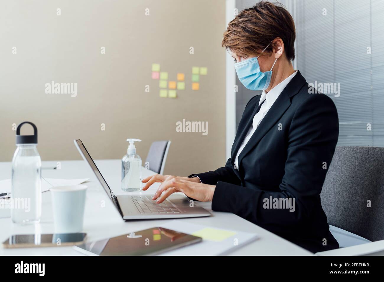 Femme d'affaires travaillant sur un ordinateur portable au bureau pendant COVID-19 au bureau Banque D'Images
