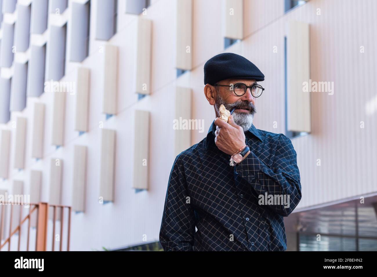 Homme mûr avec pipe fumeur qui regarde loin dans la ville Banque D'Images
