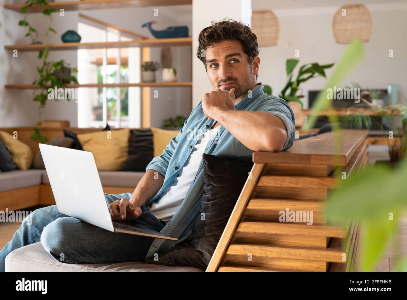 Travailleur indépendant attentionné, assis avec un ordinateur portable sur le canapé Banque D'Images