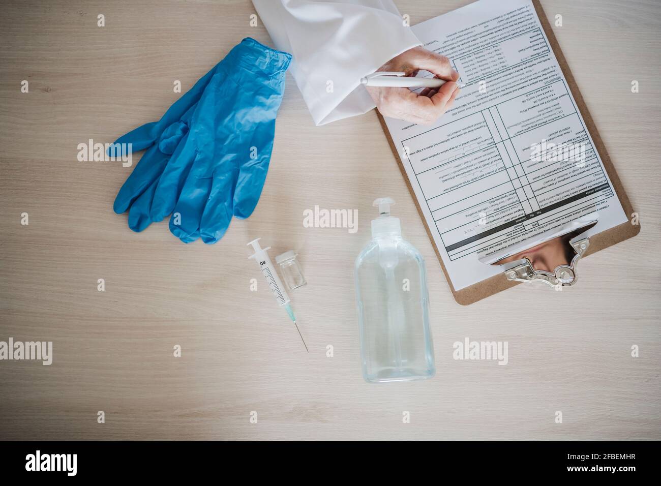 Femme médecin écrivant sur le rapport sur le presse-papiers par l'équipement médical au bureau Banque D'Images