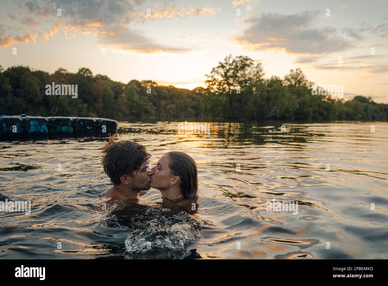 Jeune couple sautant de plate-forme de baignade sur un lac, holding hands Banque D'Images